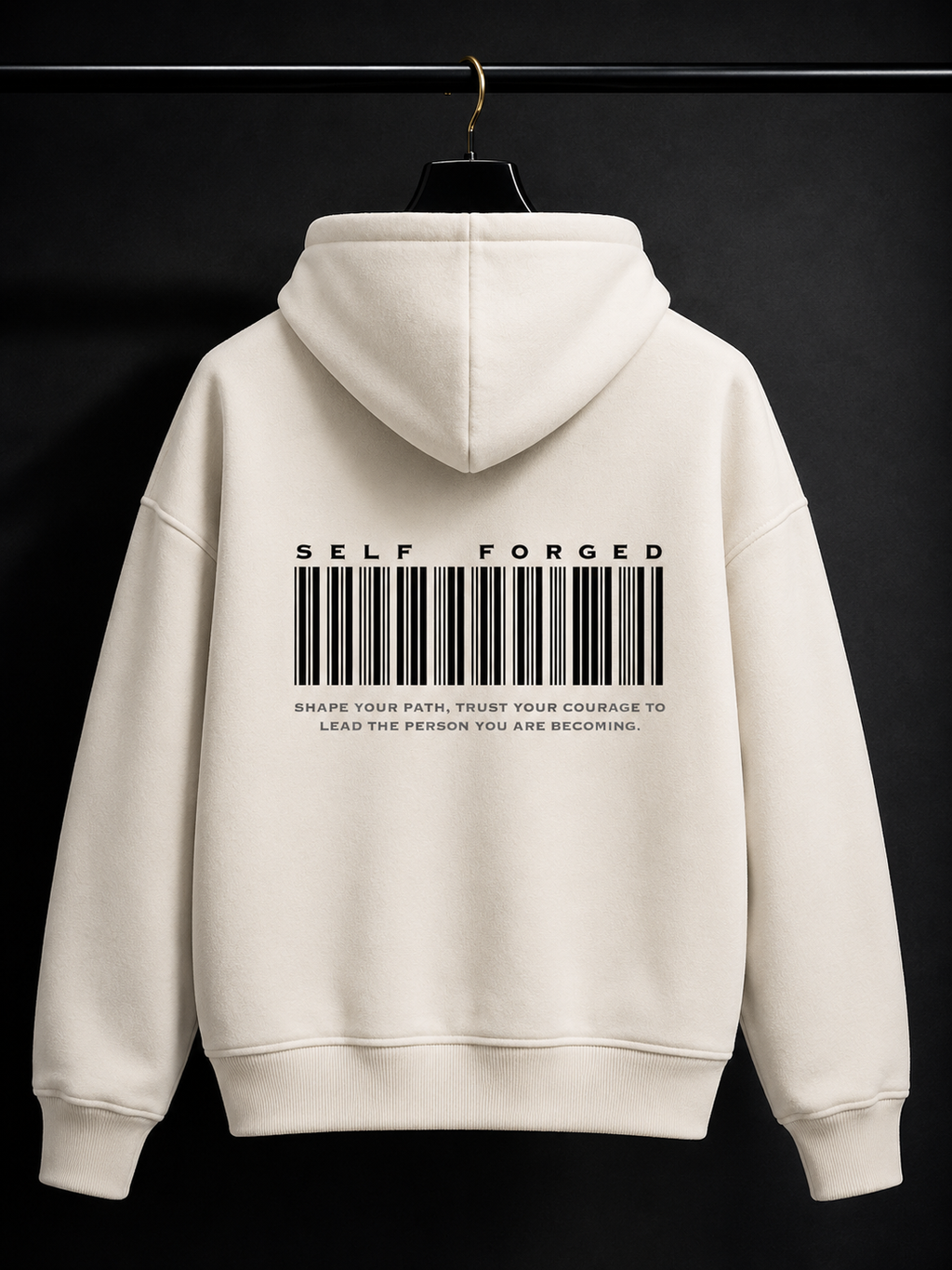 An off-white hoodie hanging on a black hanger against a dark background, featuring a black barcode graphic and the text 'SELF FORGED' printed on the back.