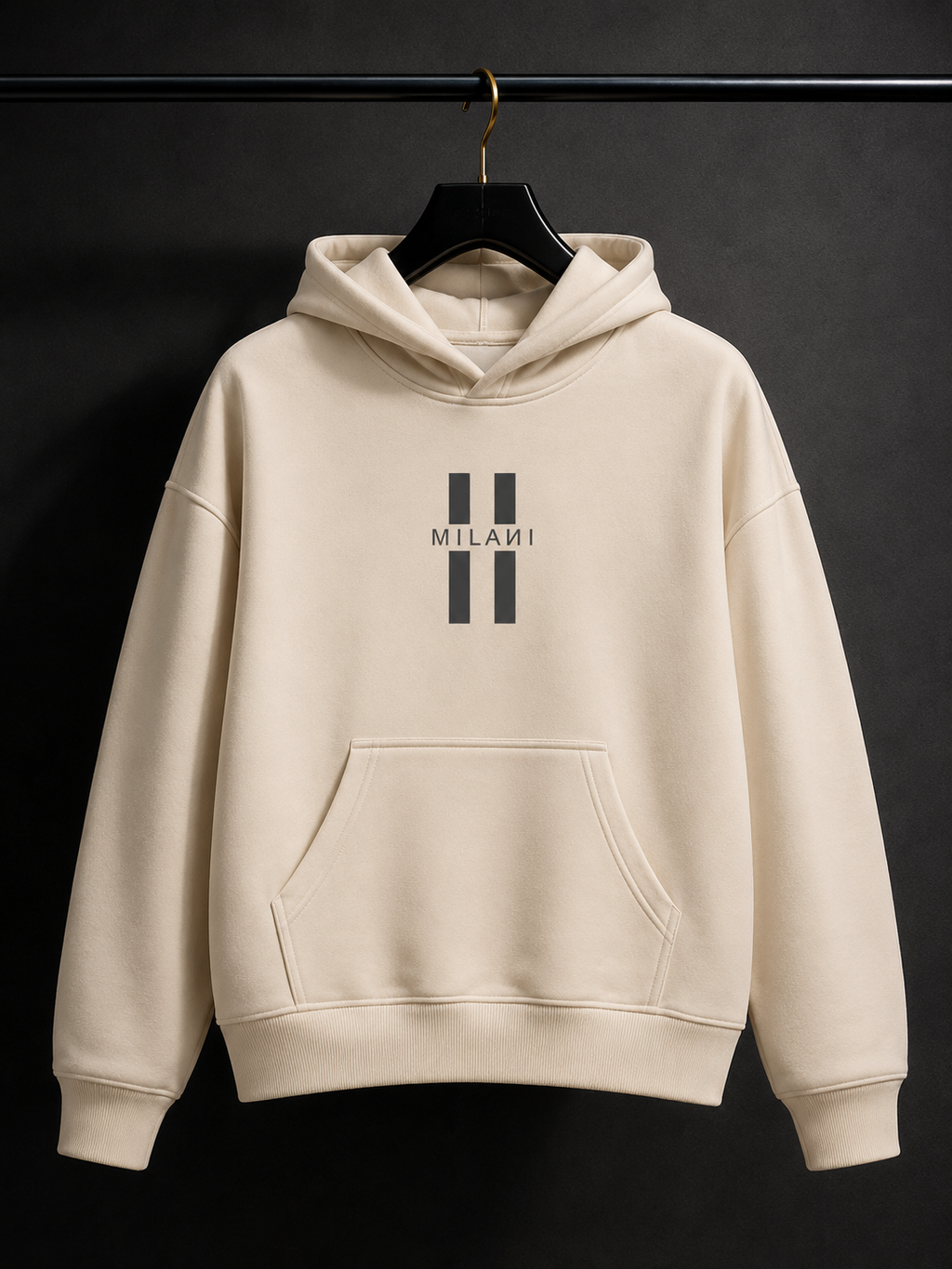 A cream-colored pullover hoodie with a black double-stripe logo and the word 'MILANI' printed on the chest, hanging on a black hanger against a dark background.