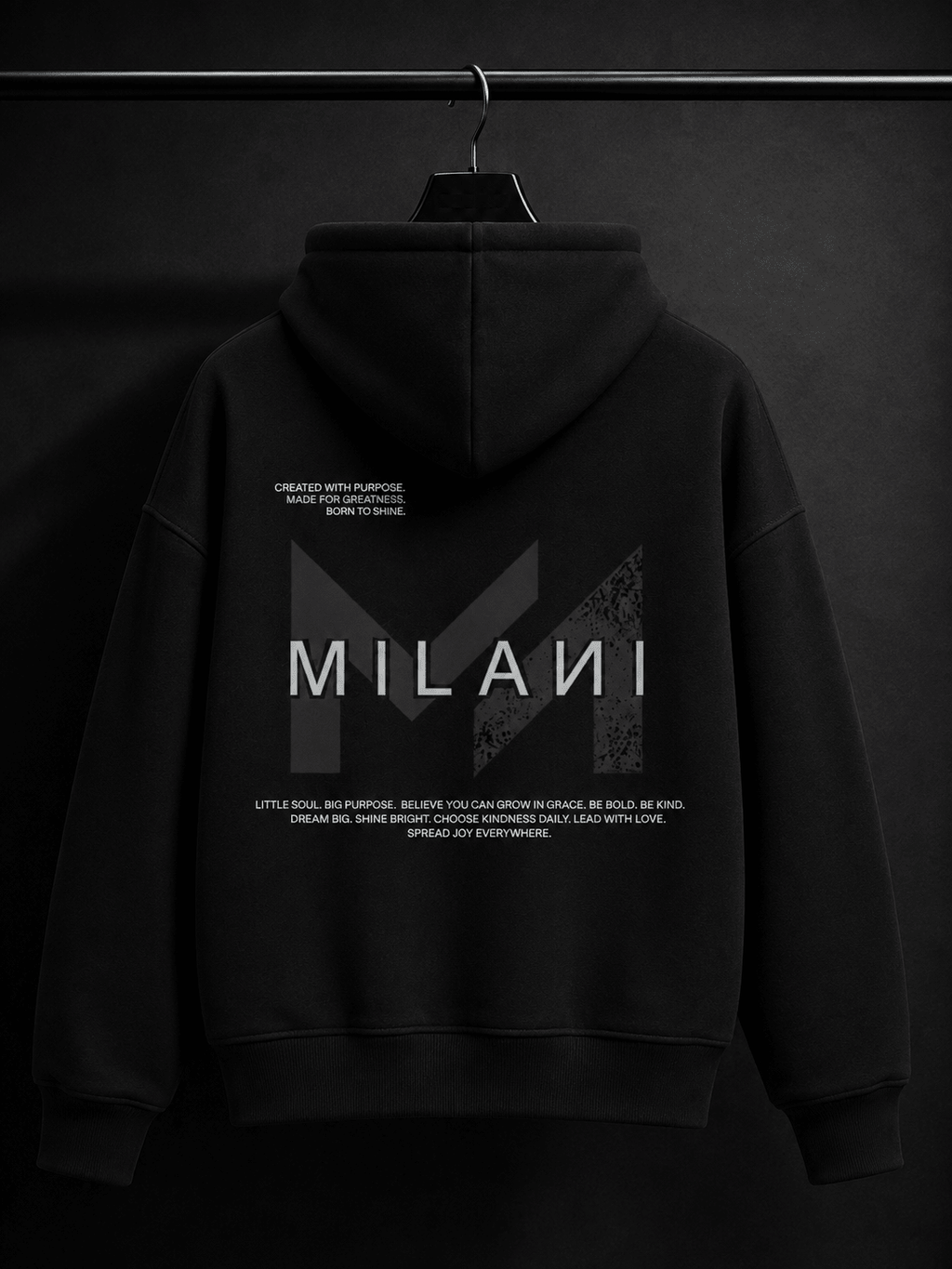 MILANI Originals Unisex Heavyweight Hoodie - Black - MILANI CLOTHINGMILANI Originals Unisex Heavyweight Hoodie - BlackMILANI CLOTHING PTY LIMITEDMILANI CLOTHING4-6 YearsA black pullover hoodie hanging on a black hanger against a dark studio background. The back of the hoodie features a large white and gray geometric 'M' logo with the word 'MILANI' across the center, plus small white text above and below.