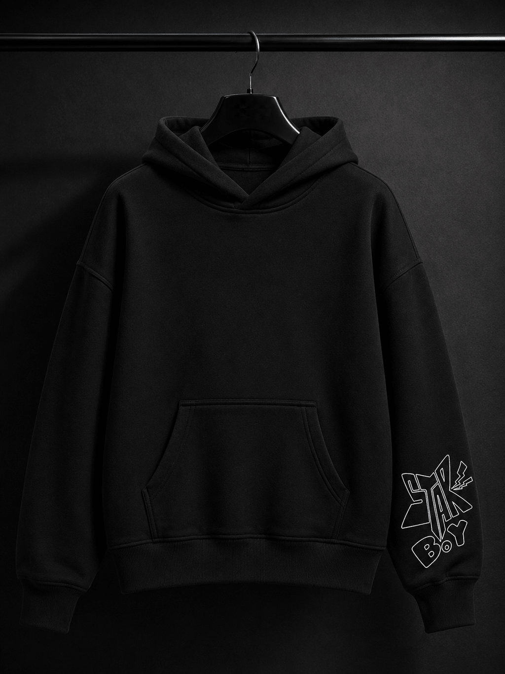 MILANI Originals Unisex Heavyweight Hoodie - Black - MILANI CLOTHINGMILANI Originals Unisex Heavyweight Hoodie - BlackMILANI CLOTHING PTY LIMITEDMILANI CLOTHING4-6 YearsA black pullover hoodie hanging on a black hanger against a dark studio background. The hoodie has a front kangaroo pocket and a white outlined graphic print on the left sleeve.